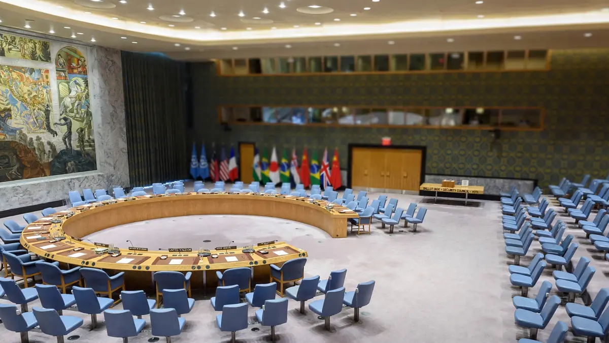 Empty UN Security Council chamber in New York with horseshoe table, national flags and a ballot box