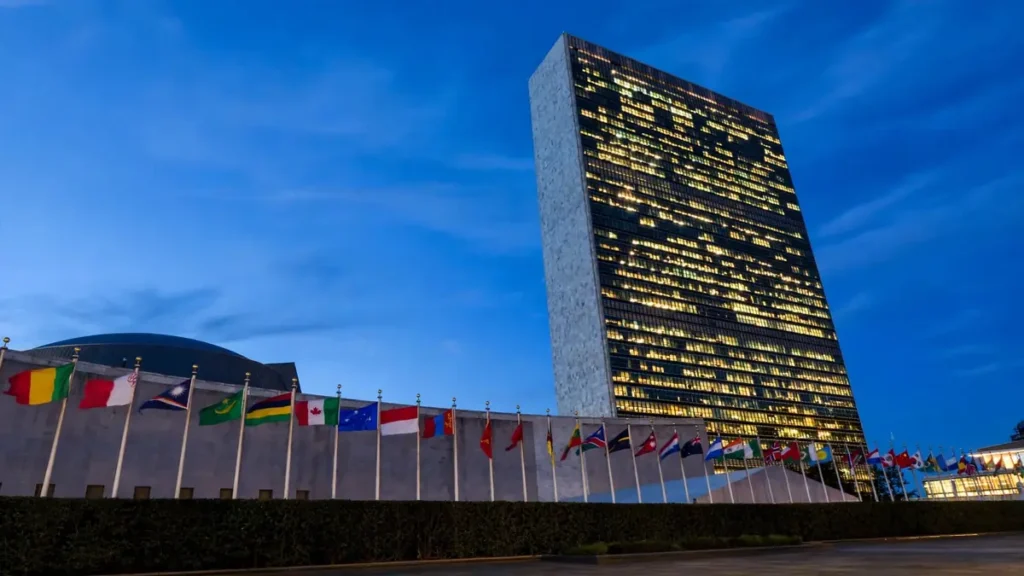 United Nations headquarters in New York at dusk with flags of member nations in front of the Secretariat building